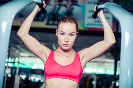 Woman athlete doing pull-ups on the bar in the gym.
