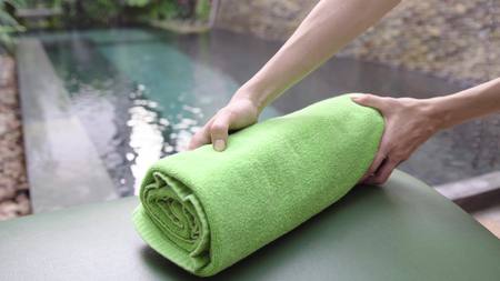 Woman putting fresh clean towel on chaise longue near pool in hotel.の写真素材