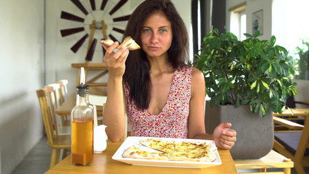 Woman eating cheese pizza sliceの写真素材