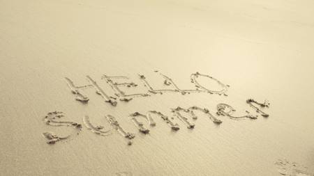 HELLO SUMMER written on the beach sand washed aways by waves.の写真素材