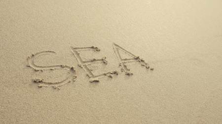 SEA with heart written on the beach sand washed aways by waves.の写真素材