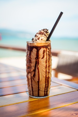 Iced blended milk and chocolate frappucino with whipped cream on beachの写真素材