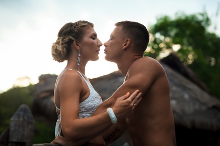 Happy romantic couple in love hug and kiss on beach at summer day