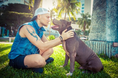 Man and dog american pit bull terrier relaxing at the park embracing and huggingの写真素材