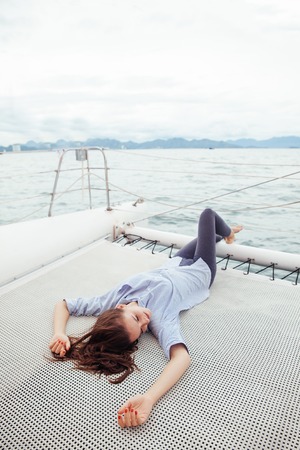 Woman lay on cruise ship deck while travelling in the seaの写真素材