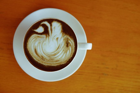 Hojicha latte with milk foam art on wooden backgroundの写真素材