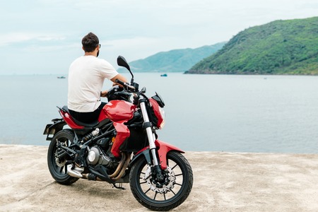 Man sitting on his motorcycle and looking at the sea