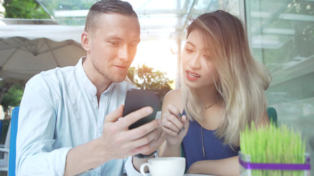 Multicultural couple using app on smartphone togetherの写真素材
