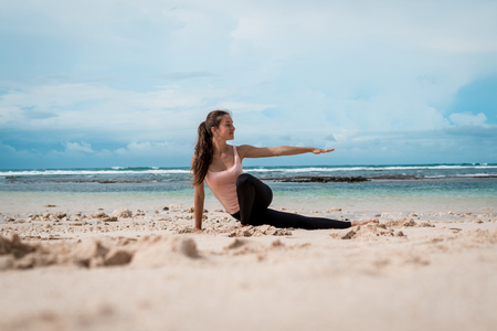 Sporty woman practicing yoga on the beach at sunrise. Healthy lifestyle.