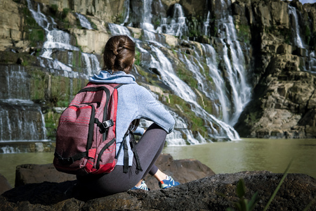 Sporty woman sitting near Pongour waterfall in Dalat, Vietnamの写真素材