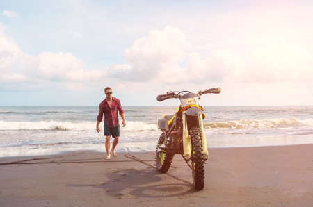 Biker man go to his sport motorbike on ocean beach.の写真素材