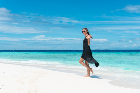 Woman walking on beach with transparent water of ocean in Maldivesの写真素材