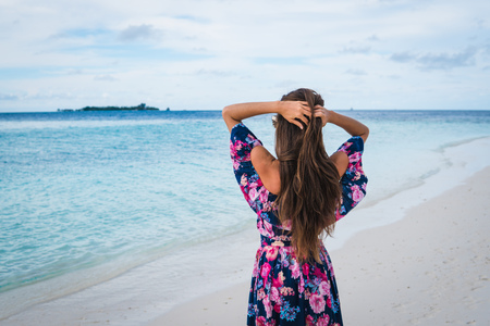 Woman in long dress on beach with pure water of ocean in Maldivesの写真素材