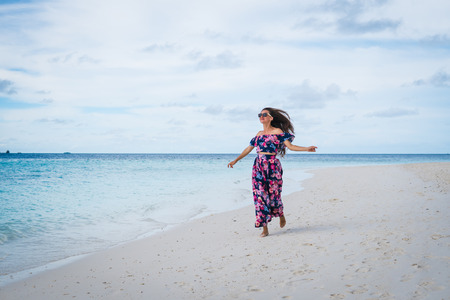Woman running on beach with transparent water of ocean in Maldivesの写真素材