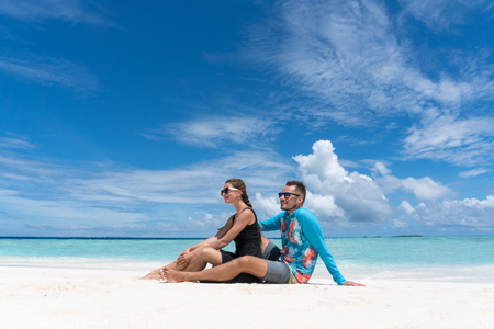 Couple sit on beach with transparent water of ocean in Maldivesの写真素材