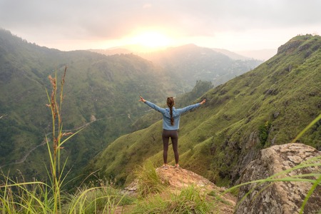 Woman standing with raised hands on the top of Small Adams peak. Ella, Sri Lankaの写真素材