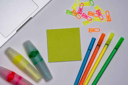 Sticky notes with markers, colored pens, paper clips laying on a table.の写真素材