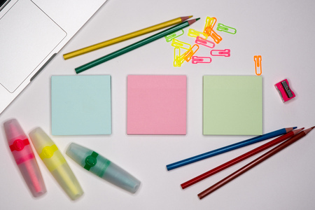 Sticky notes with markers, colored pens, paper clips laying on a table.の写真素材