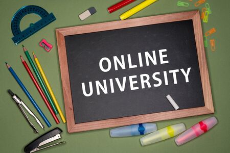 Online university written on chalkboard, stationery on green background. Remote education conceptの写真素材