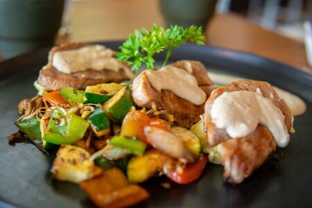 Fish dish with red tuna steak on mashed potatoes with grilled vegetables. Creamy sauce on topの写真素材