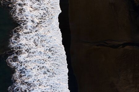 The black sand beach in Bali. Sea aerial view and top view.の写真素材