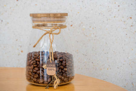 Coffee beans in glass jar on a wooden table. 100 percent Love sign and keyの写真素材