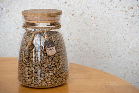 Coffee beans in glass jar on a wooden table. 100 percent Love sign on the ropeの写真素材