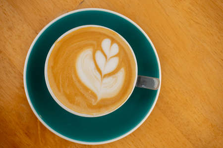 Cappuccino or latte with foam in blue cup. Top view, isolated on wood backgroundの写真素材