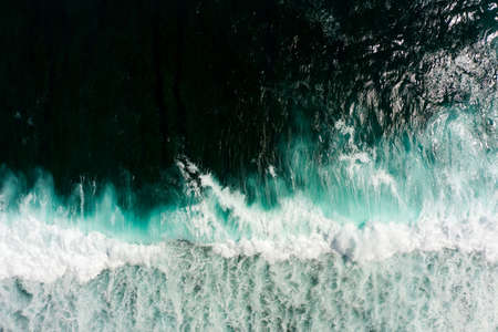 Top aerial view of giant ocean waves crashing and foaming.
