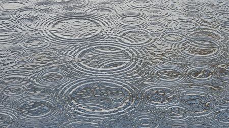 Close-up view of numerous concentric circles formed by raindrops hitting a dark, shimmering water surface, creating a mesmerizing abstract pattern.の素材