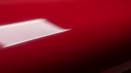 Extreme close-up of a vibrant red, glossy surface, featuring a crisp white edge and subtle light play, creating an abstract and minimalist composition.の素材
