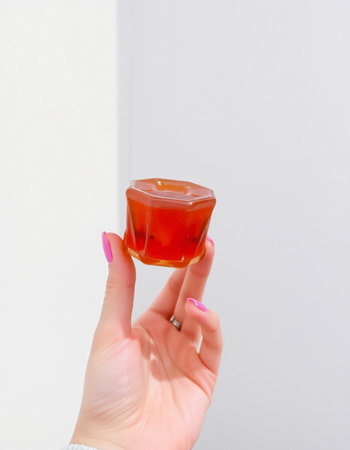 Hand of a young woman holding a cube of jelly on a white backgroundの写真素材