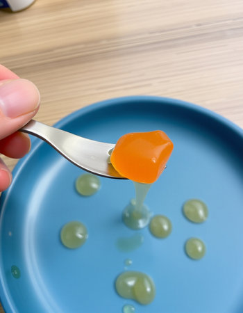 Fruit jelly candies on a blue plate with a spoon.の写真素材