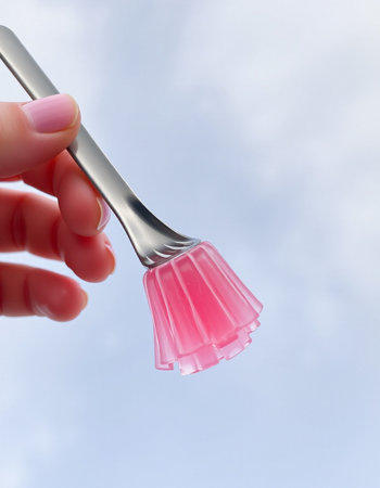 Hand holding a pink plastic paint brush with blue sky in the backgroundの写真素材