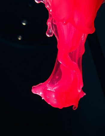 red paint splashing isolated on black background. studio shot. macroの写真素材