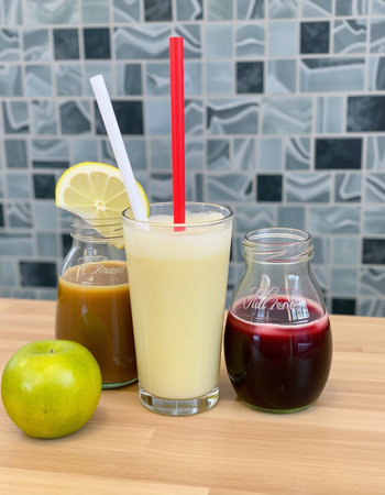 Healthy smoothie in a glass and a bottle of juice on the tableの写真素材