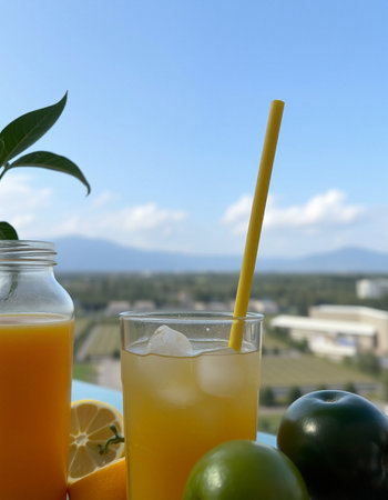Fresh orange juice in a glass with a straw on the background of the cityの写真素材