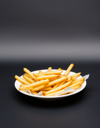 French fries in a white plate on a black background, side viewの写真素材