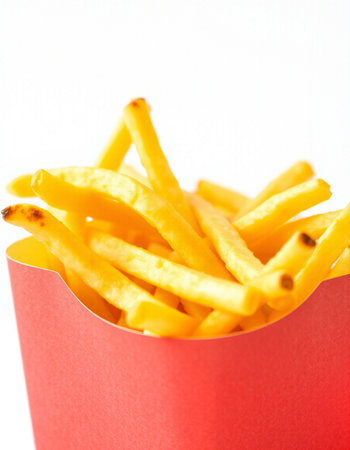 French fries in a red box on a white background. Selective focus.