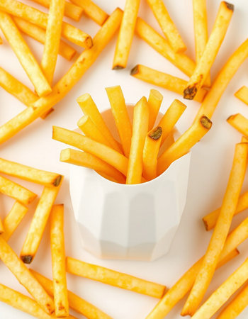 French fries in a white bowl on a white background, top view