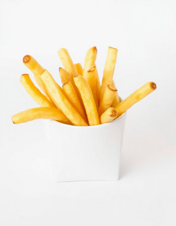 French fries in a white cup on a white background, close-upの写真素材