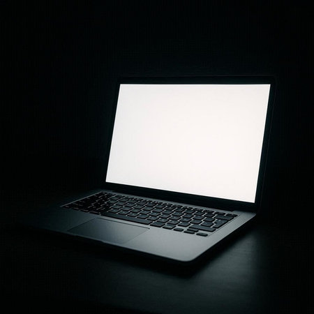 Laptop with blank white screen on black background, copy space.