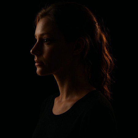 Portrait of a beautiful young woman in profile on black background.