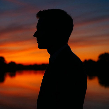 Silhouette of a man at sunset on the river bank.