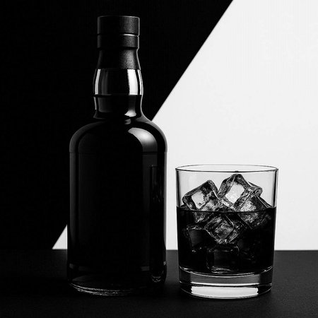 Bottle of whiskey with ice cubes on black and white background.