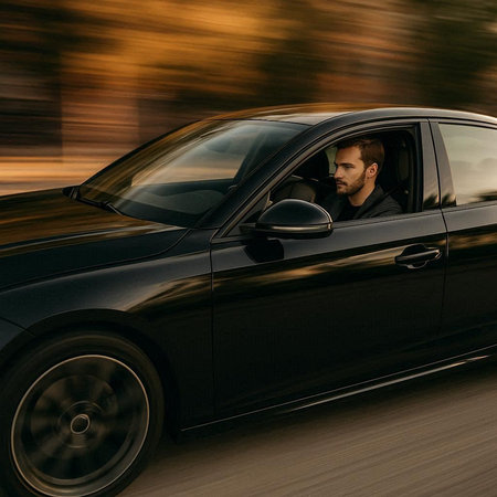 Handsome man driving a black car on a road in motion blur