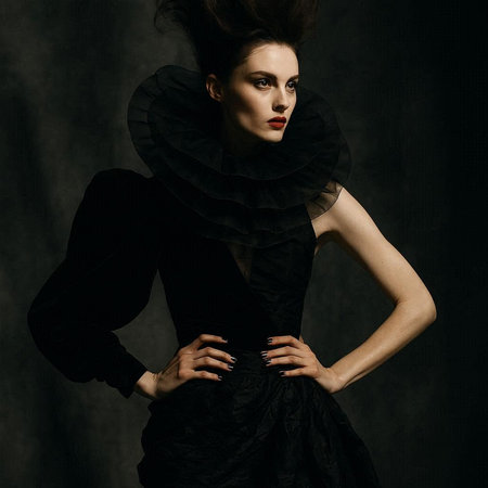Fashion portrait of young beautiful woman in black dress and hat.