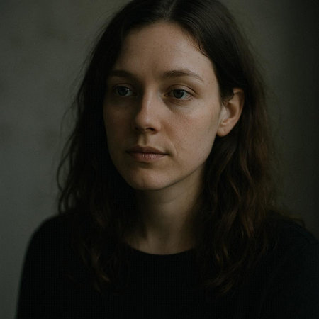 Portrait of a young woman with brown hair. Dark background.