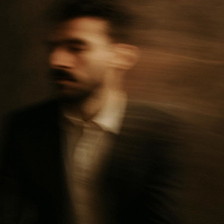 blurry portrait of a young man in a suit in the dark