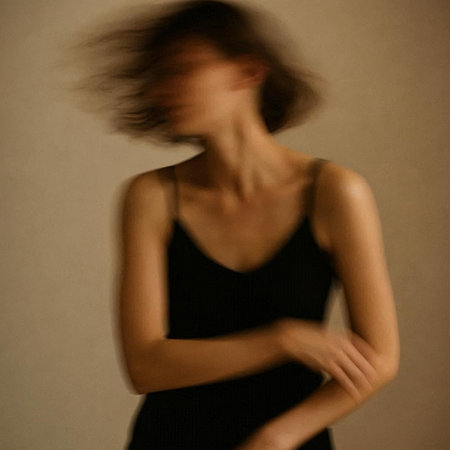 Young beautiful woman in black dress with long hair in motion blur.